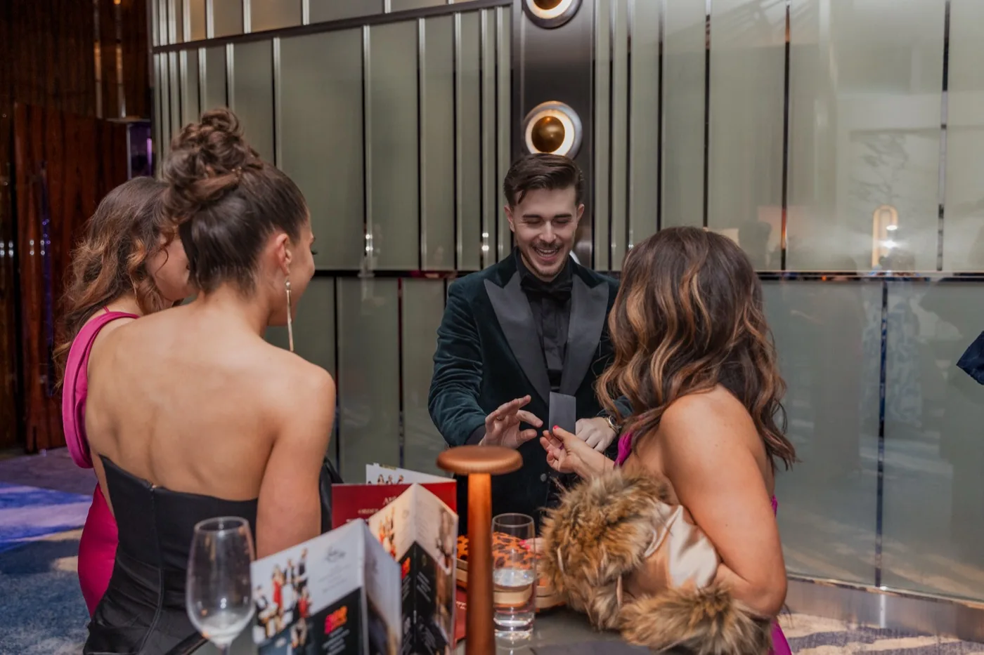 Wedding guests laughing as Cameron Leo performs close-up magic during cocktail hour