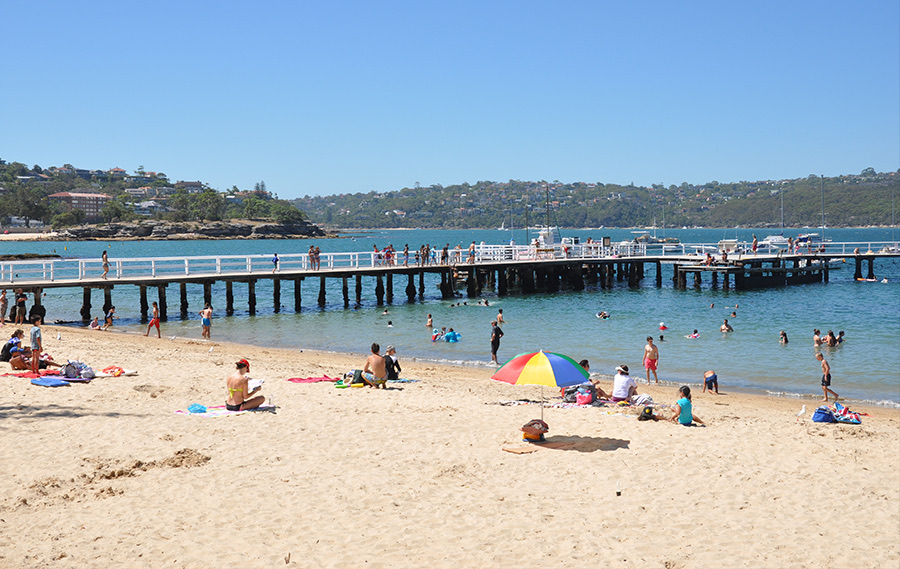 Swimmers at Balmoral Beach beside the jetty of the netted Balmoral Baths
