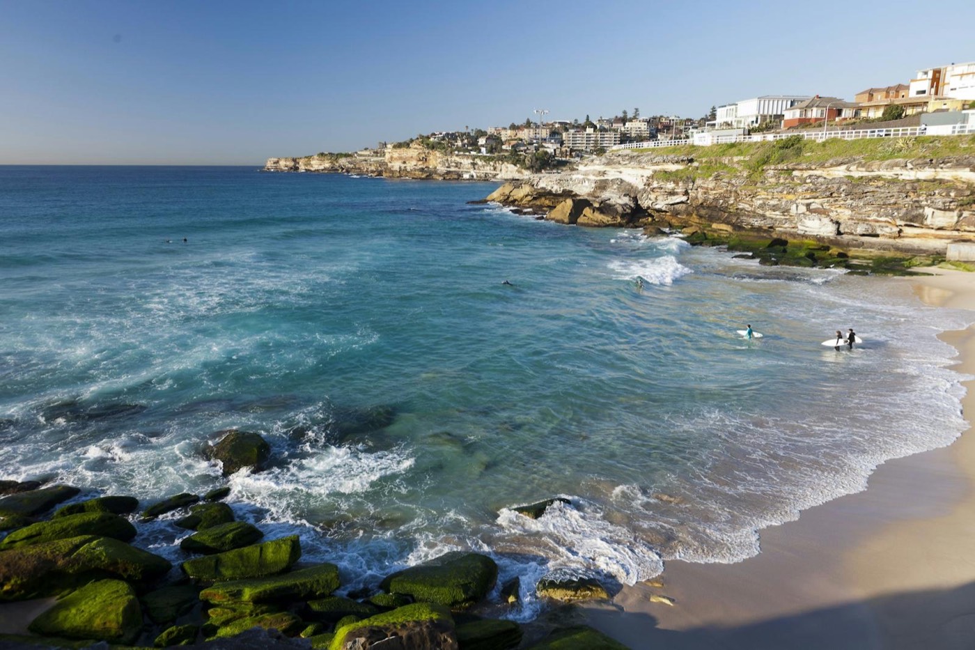 Surfers in the waves at small, rocky Tamarama Beach