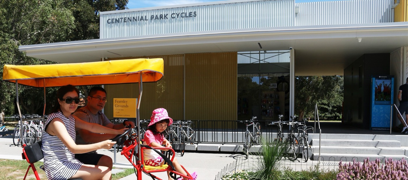 Family on a pedal car outside Centennial Park Cycles in Centennial Park