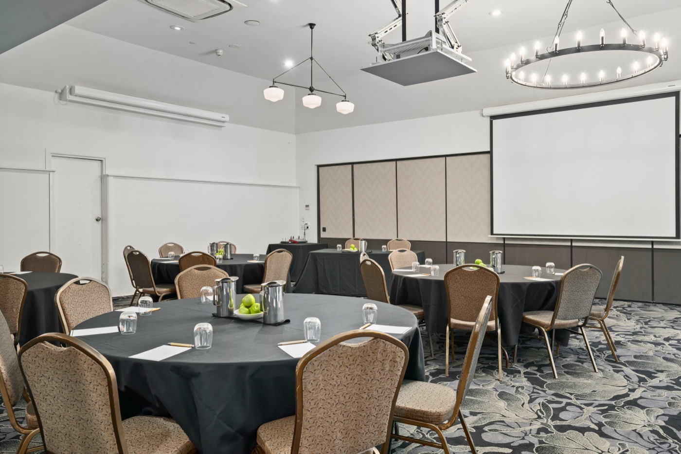 Peppers Craigieburn conference room set with round tables and a projector screen