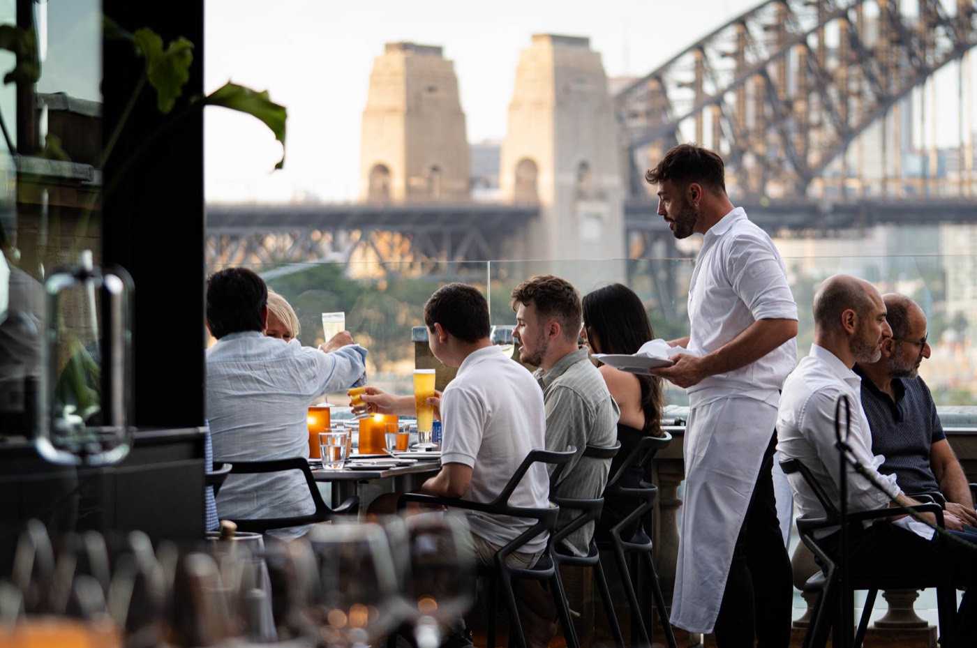 Diners on the Cafe Sydney terrace with the Harbour Bridge behind
