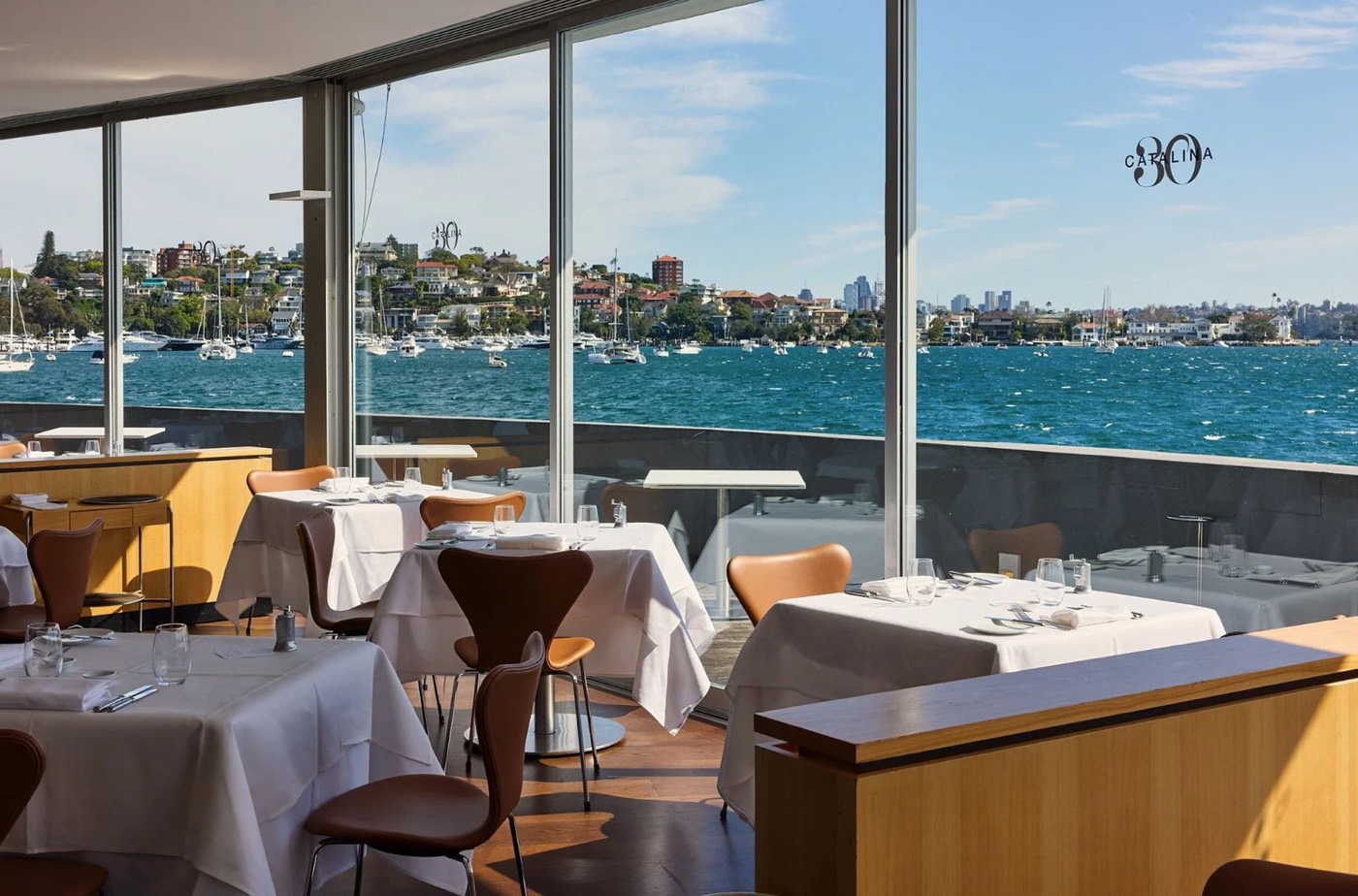 Catalina's white-clothed dining room with windows over Rose Bay