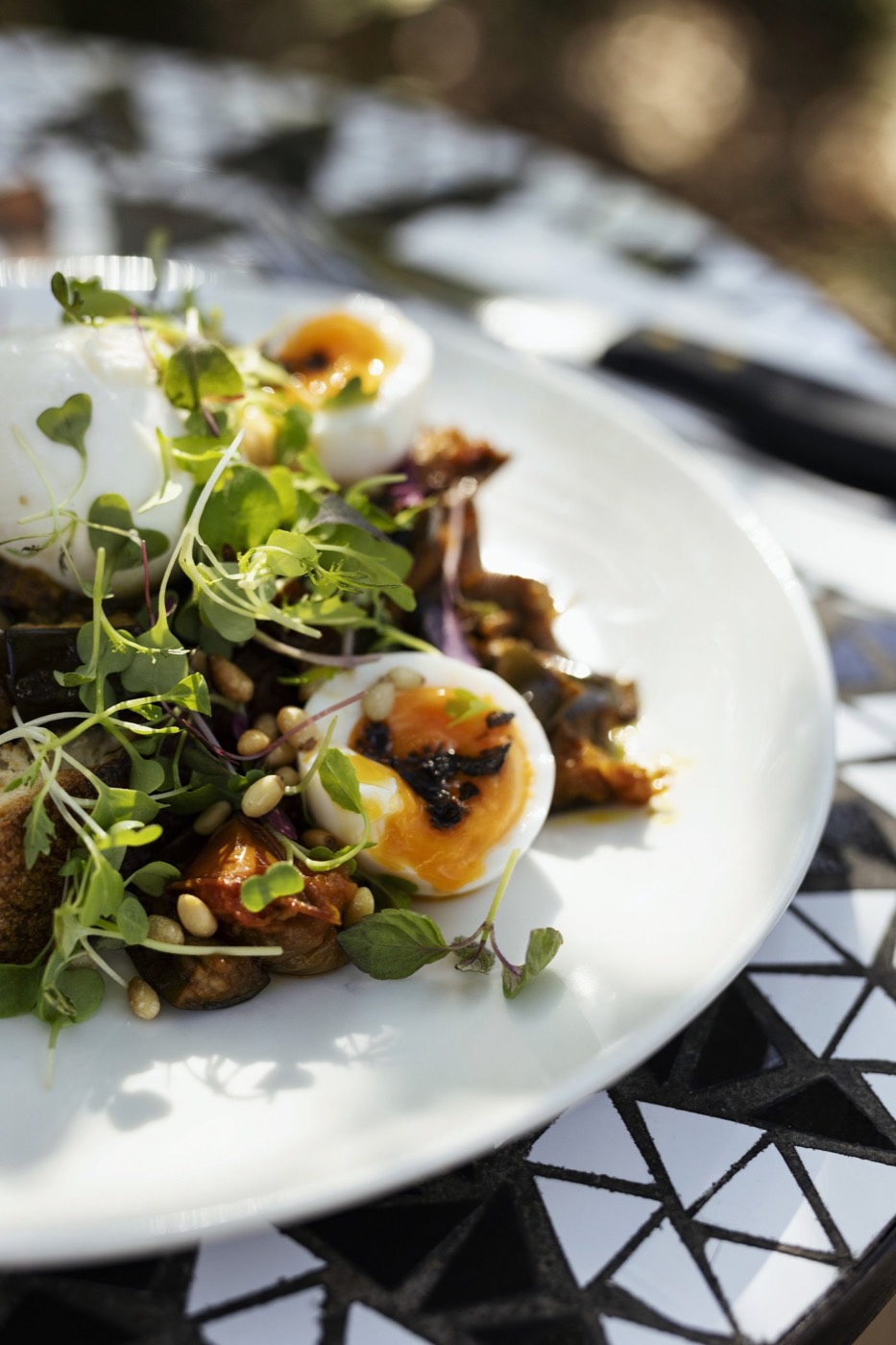 Soft-boiled eggs with greens and seeds on a plate at Kepos Street Kitchen