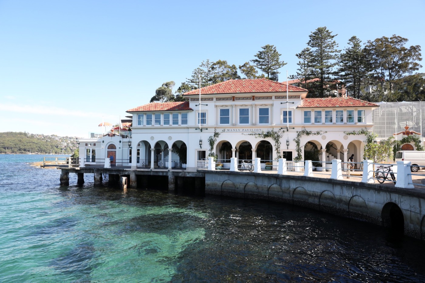 Manly Pavilion's white heritage building over the clear water of Manly Cove