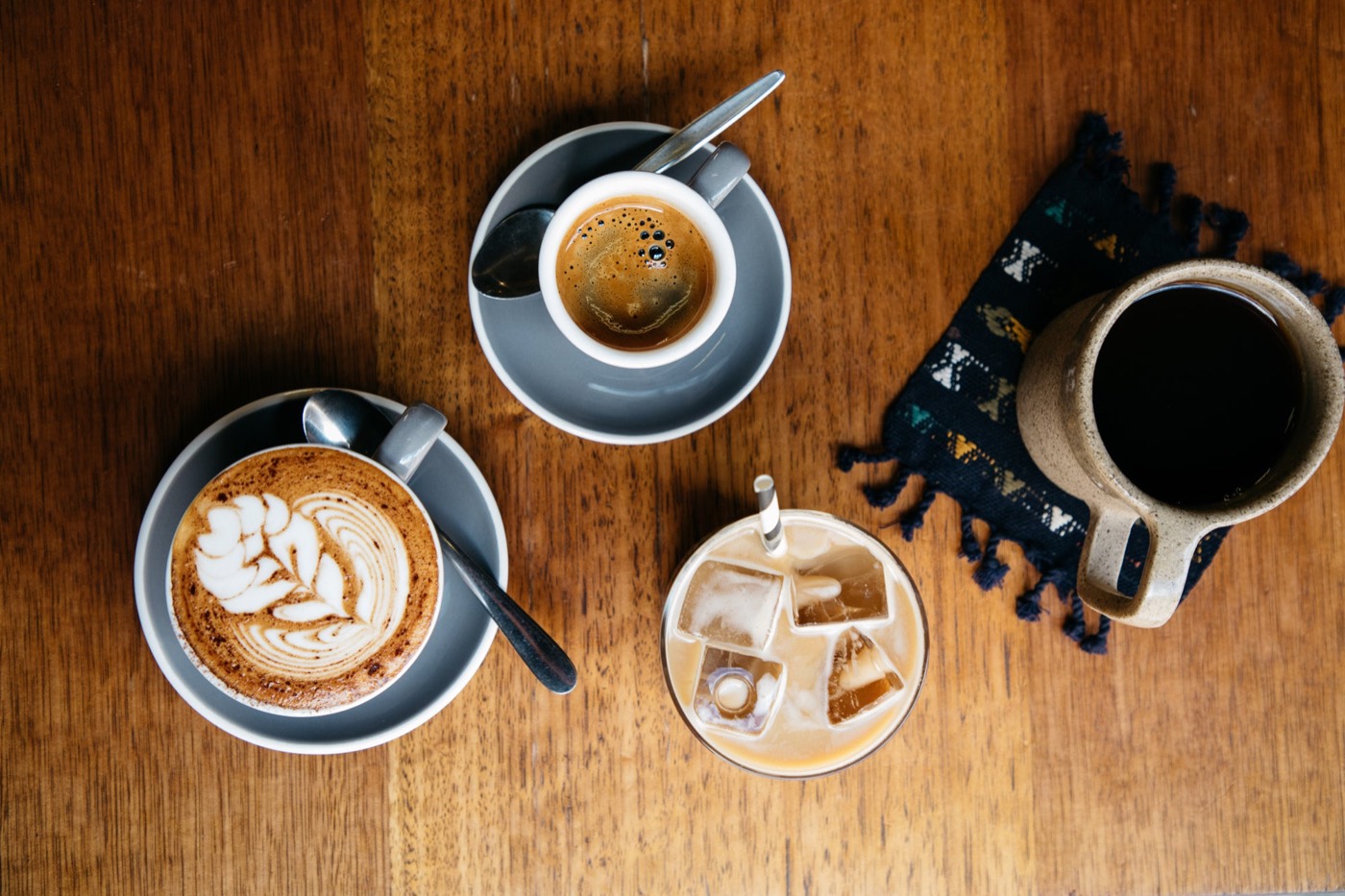 Flat white, espresso, iced coffee and filter coffee on a timber table at Reuben Hills