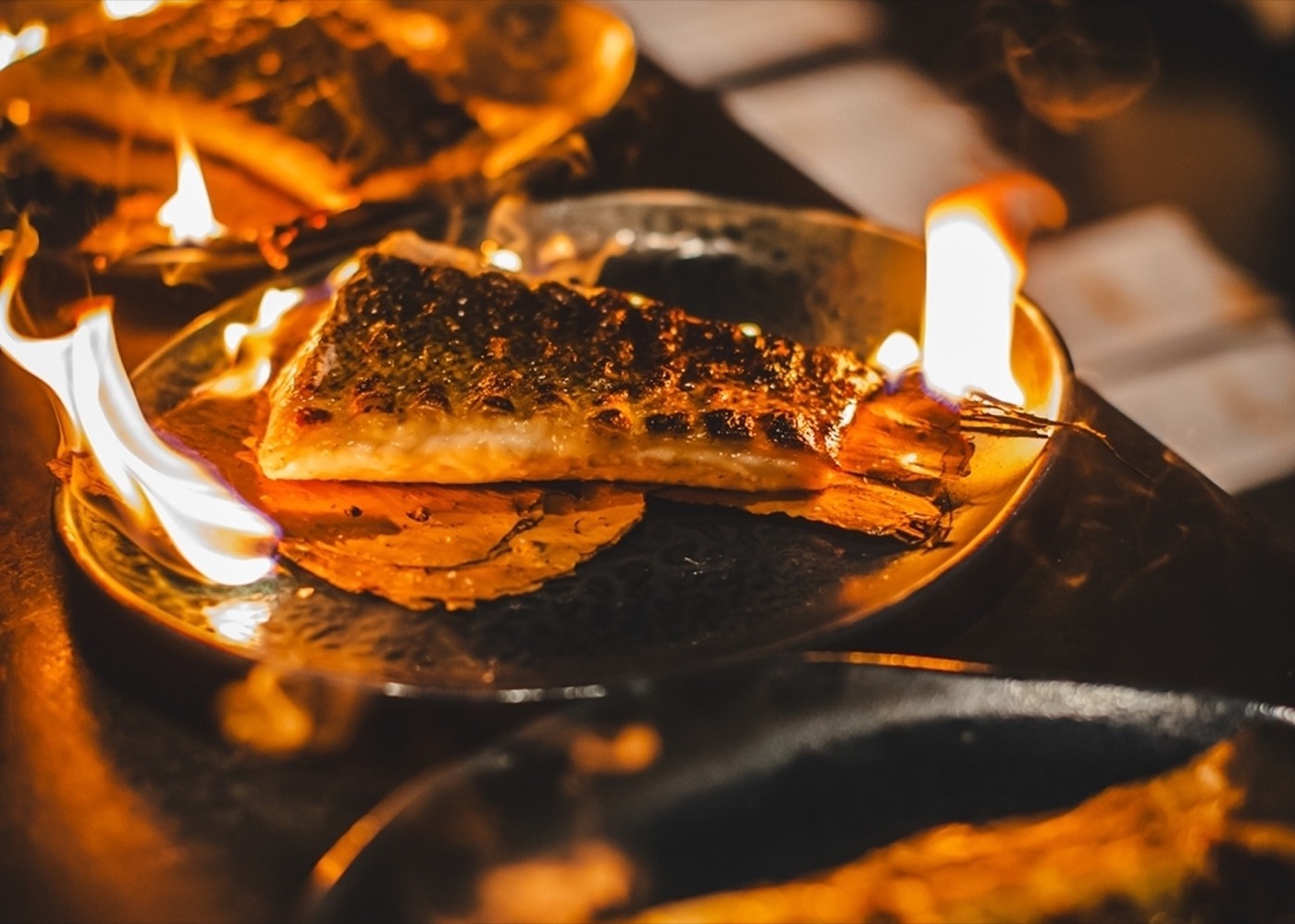 Fish fillet cooking in flames over the wood fire at Firedoor