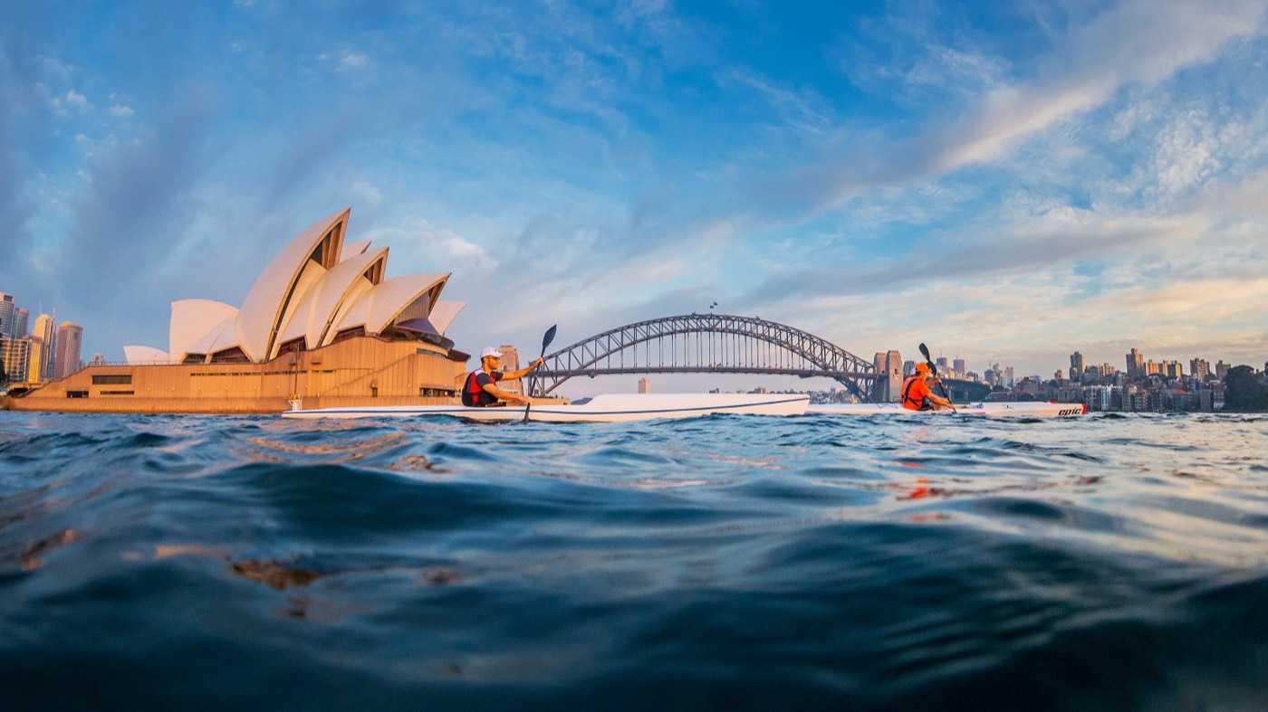 Kayakers paddling on Sydney Harbour in front of the Opera House and Harbour Bridge