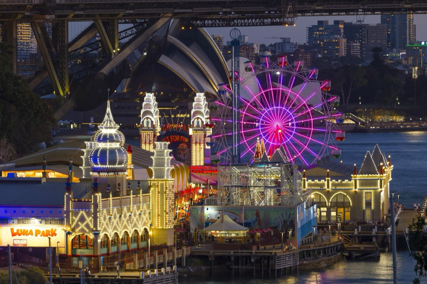 Luna Park Sydney lit up at night beneath the Harbour Bridge