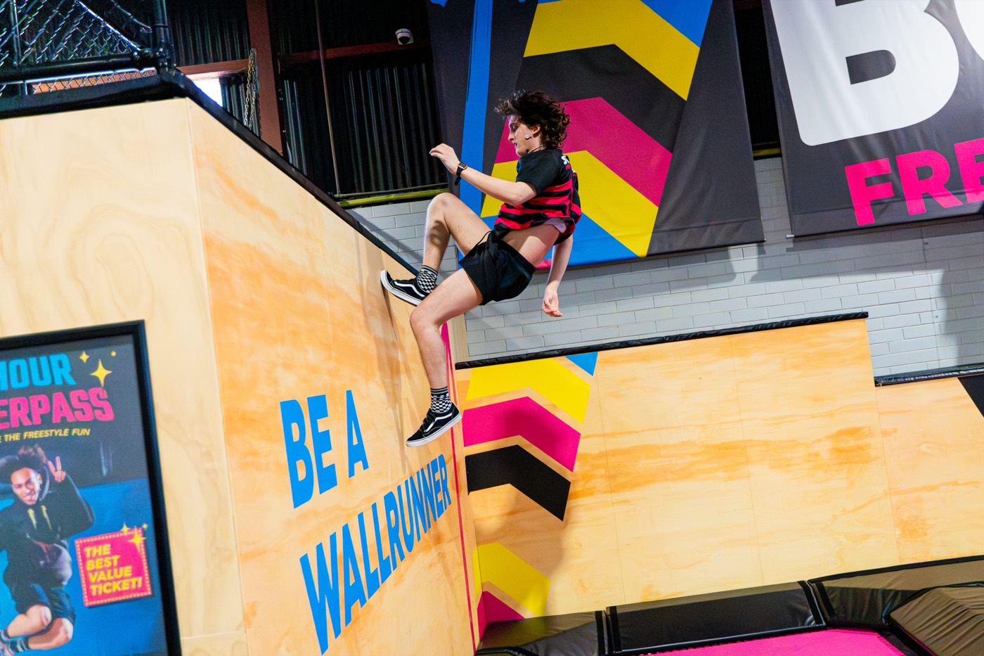 Kid running up the wall-runner ramp at a BOUNCE trampoline park