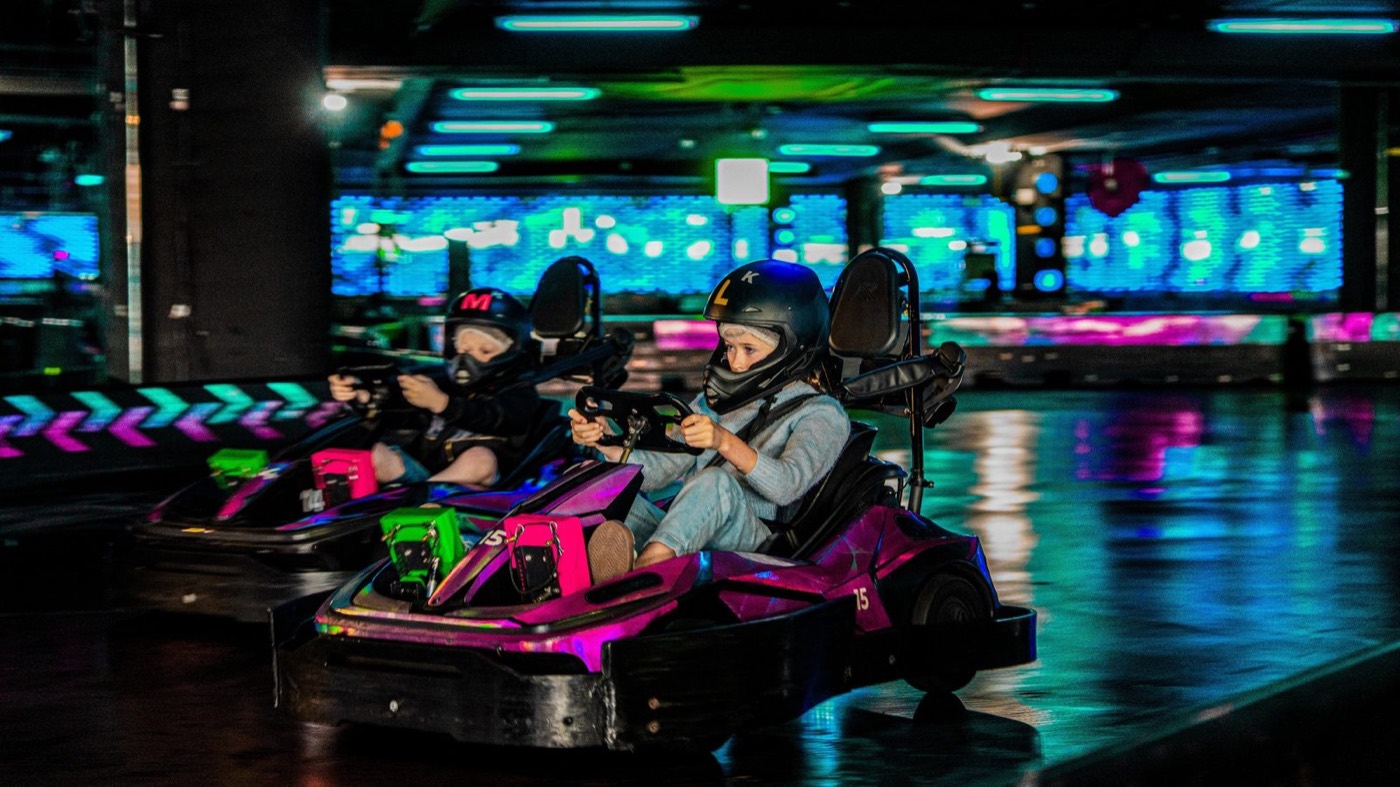 Children racing go-karts under neon lights at Hyper Karting