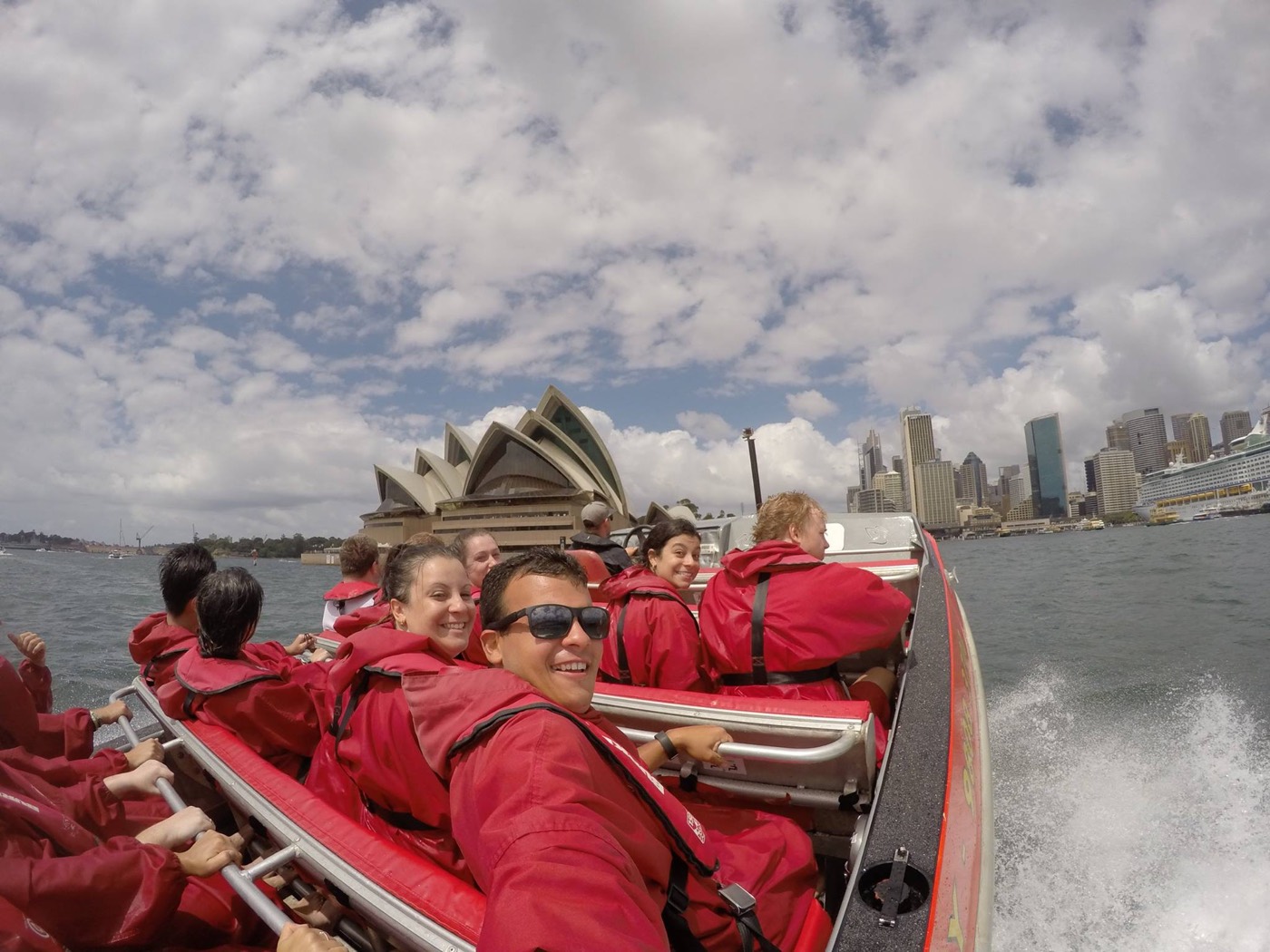 Passengers in red ponchos on an Oz Jet Boating ride past the Sydney Opera House