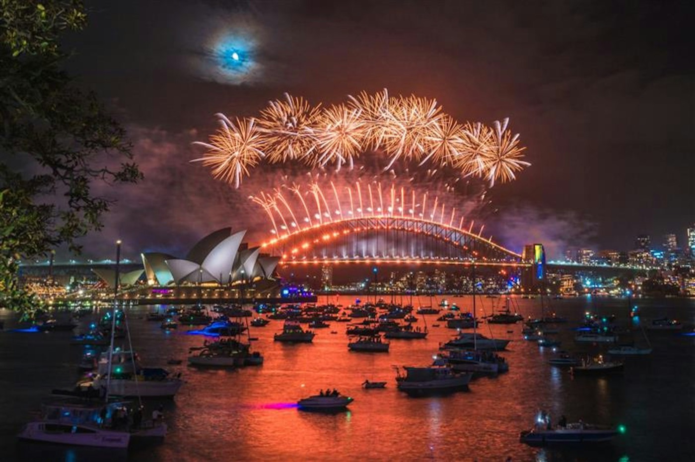 Midnight fireworks over the Sydney Harbour Bridge and Opera House with boats on the harbour