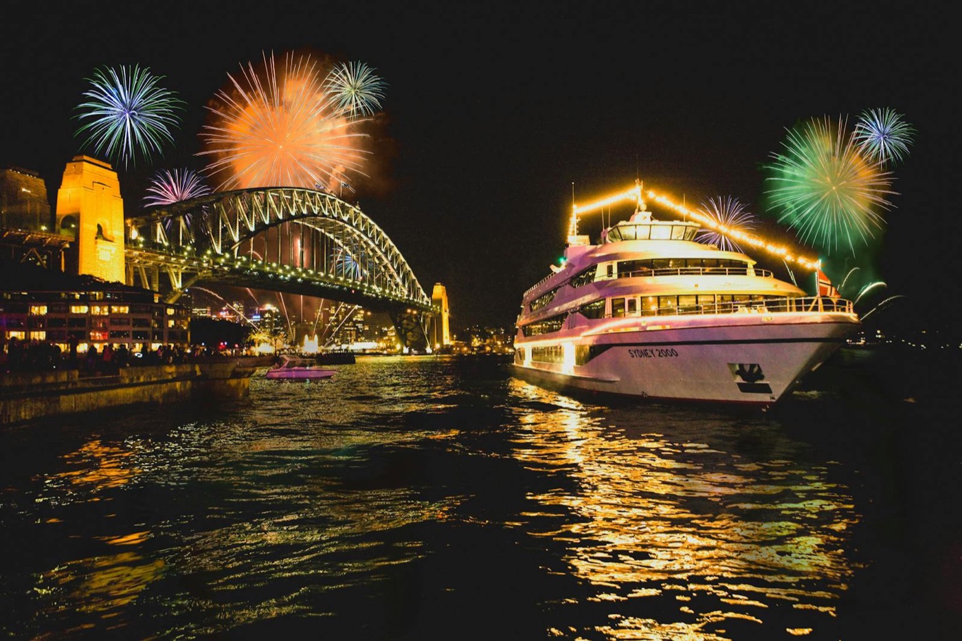 The lit-up Sydney 2000 cruise ship on the harbour with fireworks over the Harbour Bridge