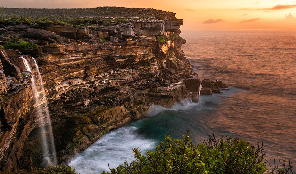 Waterfall plunging off sandstone sea cliffs on the Coast Track, Royal National Park