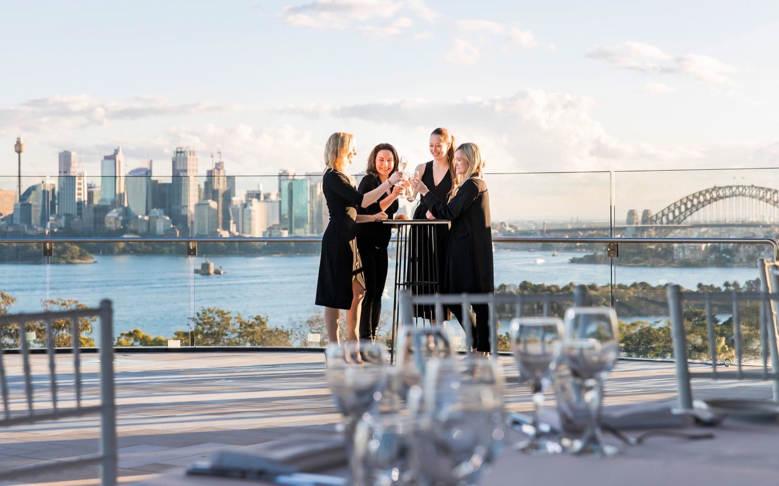 Guests toasting on a Taronga function terrace overlooking the harbour, city and Harbour Bridge