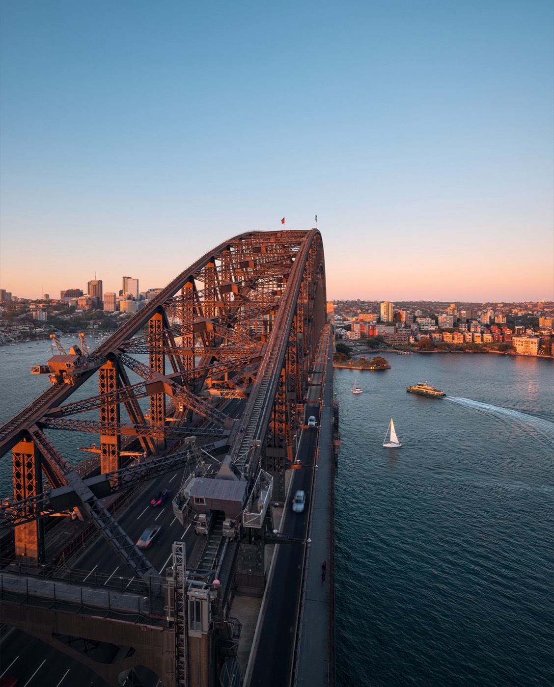View along the Sydney Harbour Bridge arch and deck towards Milsons Point at sunset