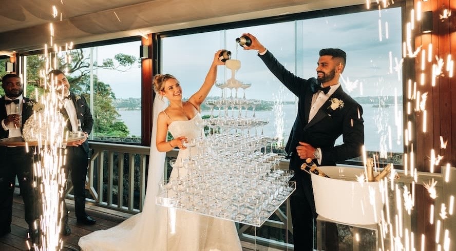 Couple pouring a champagne tower in the Gunners' Barracks dining room above the harbour