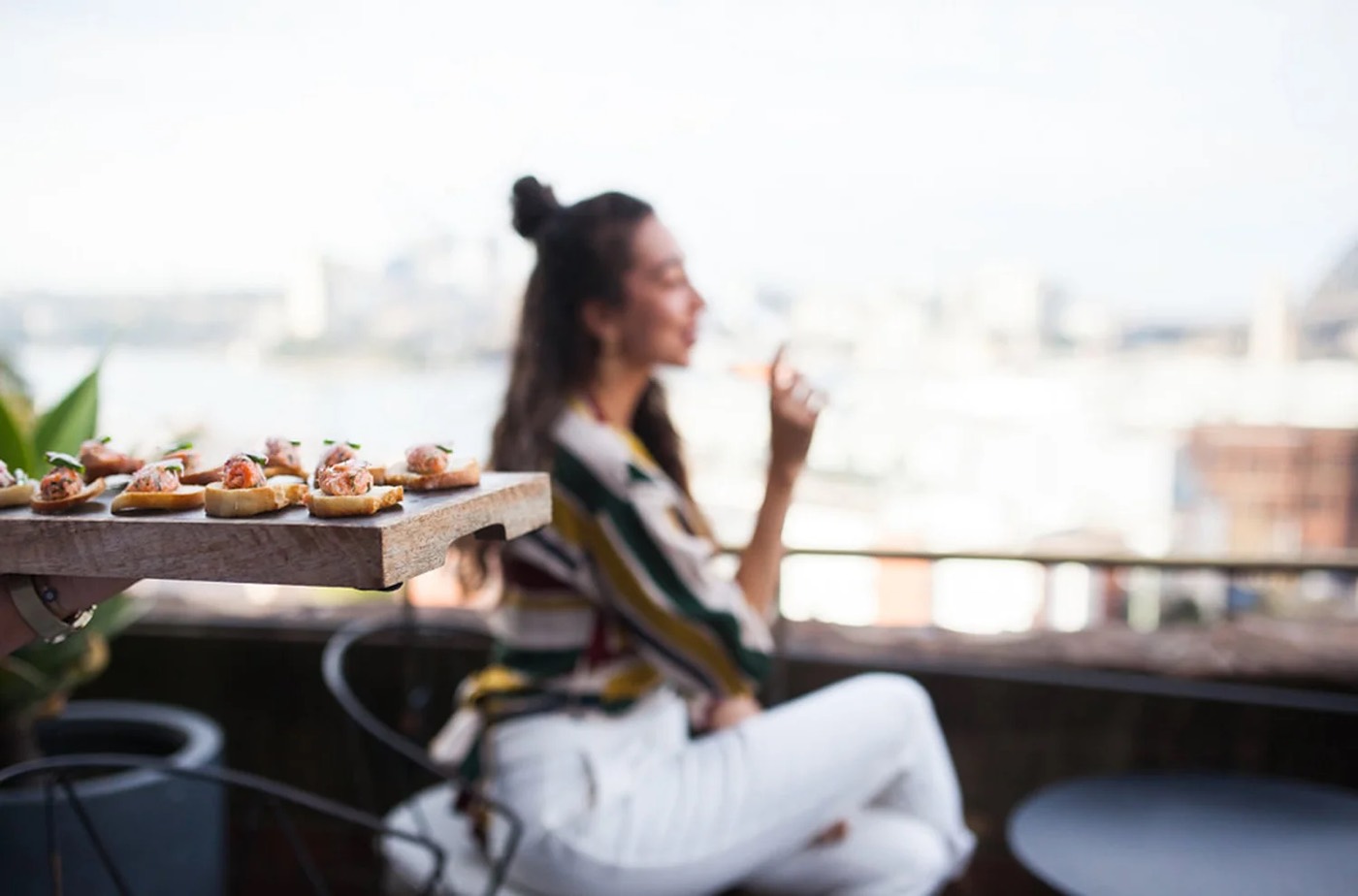 Guest relaxing with canapés on a Hotel Palisade balcony above the harbour