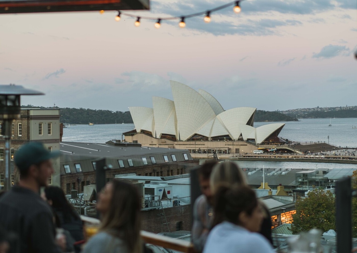 Guests on The Glenmore's rooftop with the Opera House across the harbour