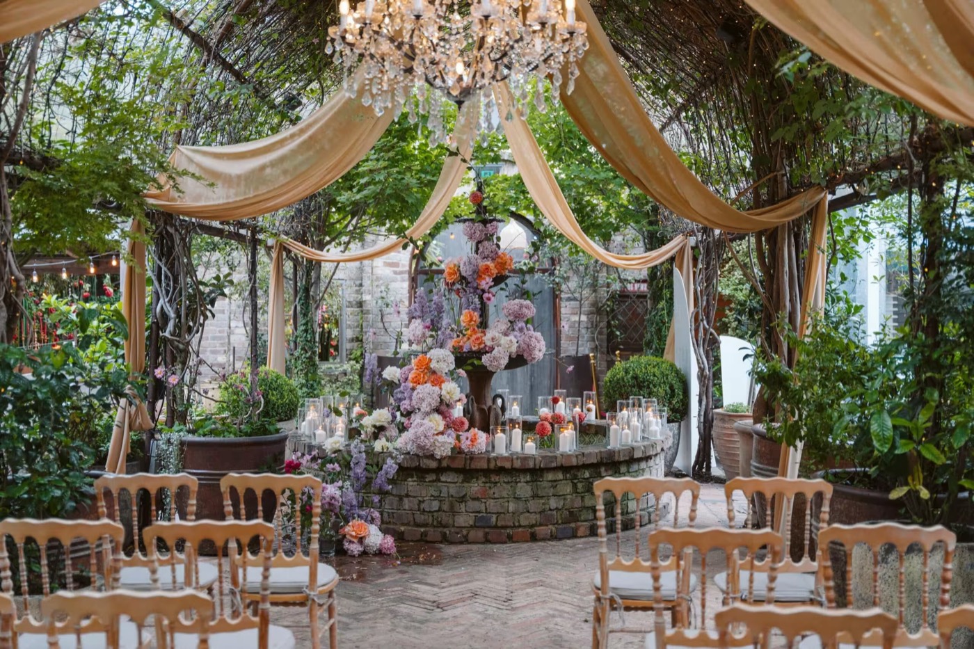 Wedding ceremony chairs under draping and a chandelier in The Garden at The Grounds of Alexandria